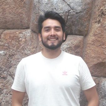 Joaquin Ramirez in a white t-shirt, smiling in front of a stone wall